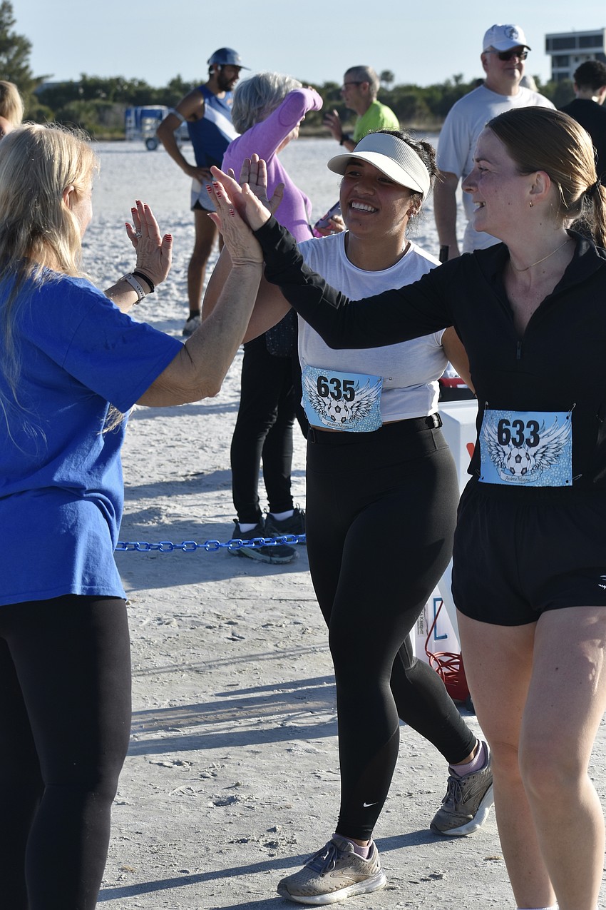 Stacey Monroe slaps hands with Louisa Tiriobo and Caitlin Lawless.