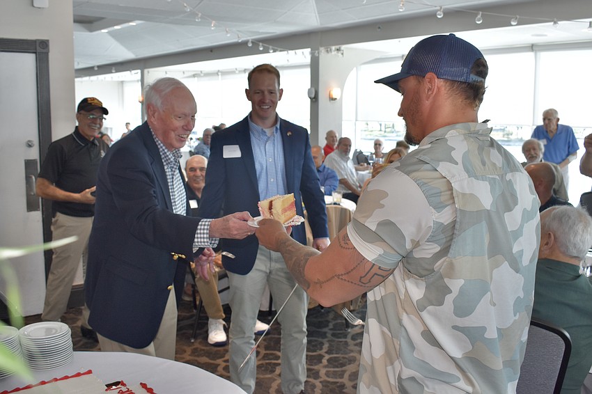 David Beliles, at 93, passed a piece of cake to the youngest Marine in the room, Tony Fudoli, 32, at the 2023 luncheon. Standing behind the table is Beliles’ grandson, Brian Walsh, a lieutenant colonel in the Marines.