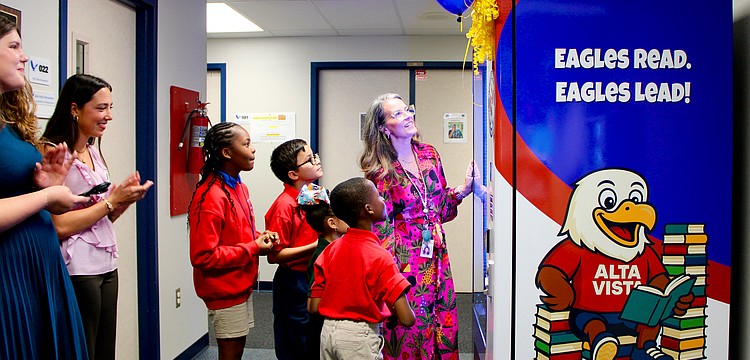Bonnie Michaels, literacy coach at Alta Vista Elementary School, helps students Deja (5th grade), Gianni (4th grade), Yoselyn (1st grade) and Andre (2nd grade) try out the new book vending machine. Sarasota Yacht Club youth board members coordinated the installation to help promote strong reading habits.
