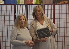 Gardeners Out East president Nancy Schneider gives the plaque for the Japanese blueberry tree that the group donated to Simone Rose, who works as the office manager for Robert Toale & Sons Celebration of Life Center.