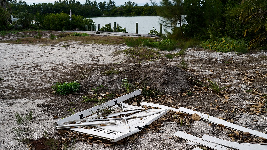 A vacant lot on N. Shore Road has some weed growth and is littered with debris from a fallen fence.