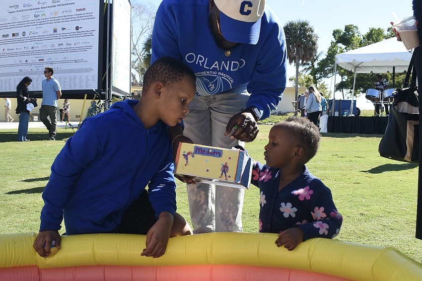 Mark Alexis (center), helps Legend Alexis, 9, and Light Alexis, 2, draw prizes after the game of fishing for rubber ducks.