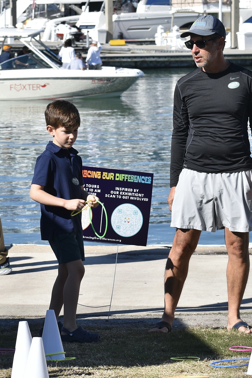 Hudson Bloom, 7, and Justin Bloom toss rings at the booth by Harvest House.