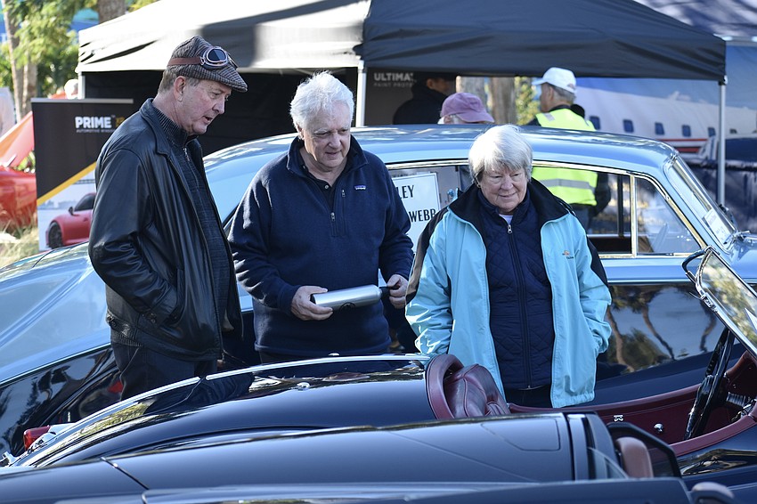 Zack Hamric shows his 1956 Jaguar XK140 MC, which was formerly owned by Michael Douglas and Catherine Zeta-Jones to Larry Powell and another attendee, Debbie Wilson.