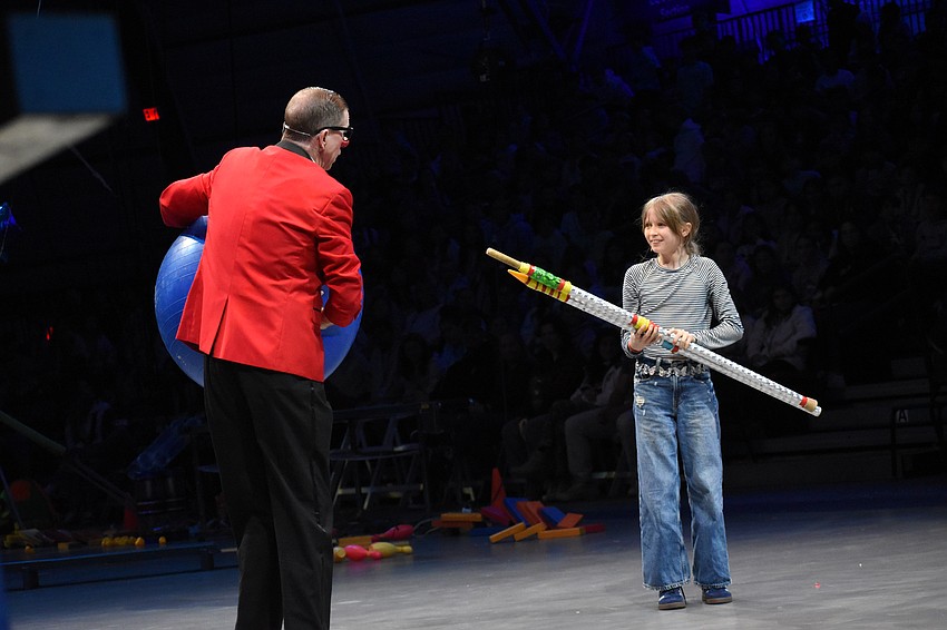 Elle Capel-Davies, a fifth grader at Bay Haven School of Basics Plus, pepares to hand Chris “Bucky” Allison a pole so he can demonstrate concepts including torque, friction, angular momentum and centripetal force with a ball.