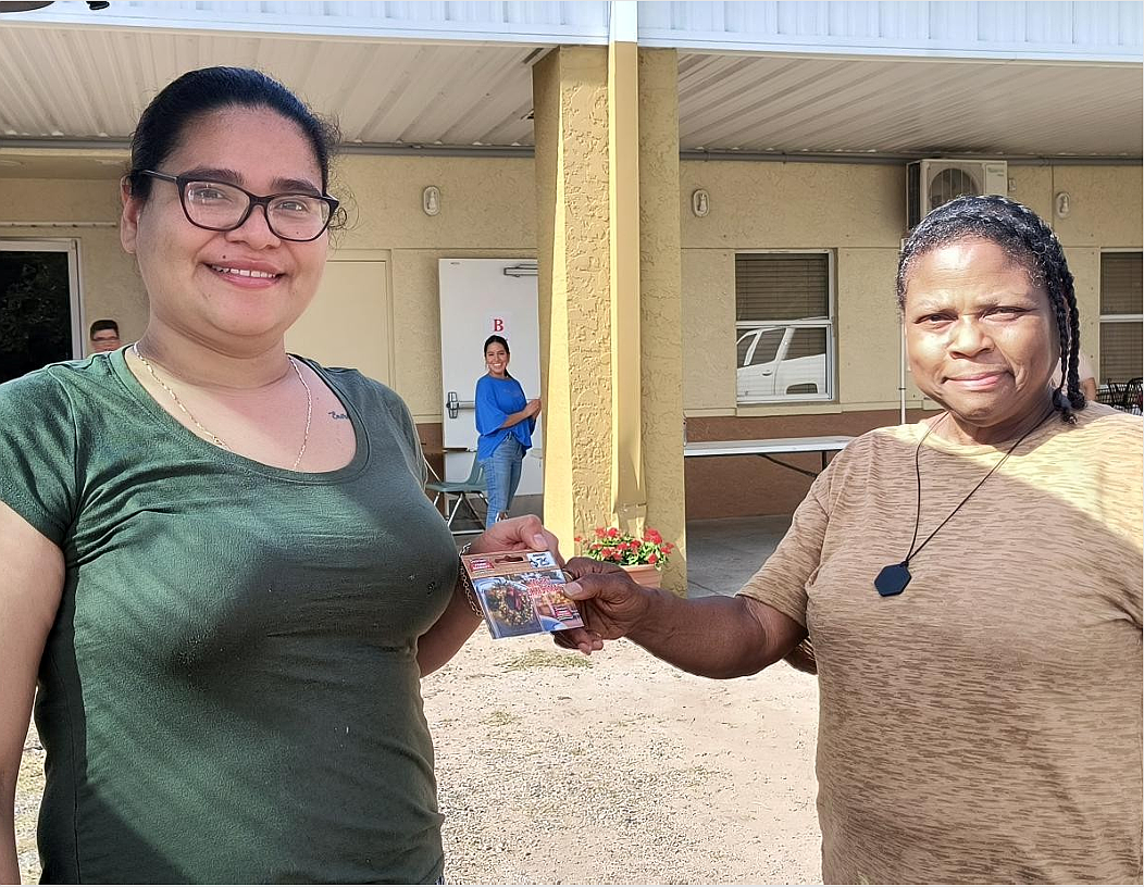 A registrant receives a gift card from volunteer Moana Dooley (right).