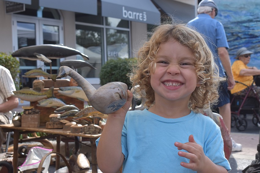 Bradenton's Noah Grafton, 2, checks out a handmade wooden sculpture created by Chris Boone at the Swan Shadow booth.
