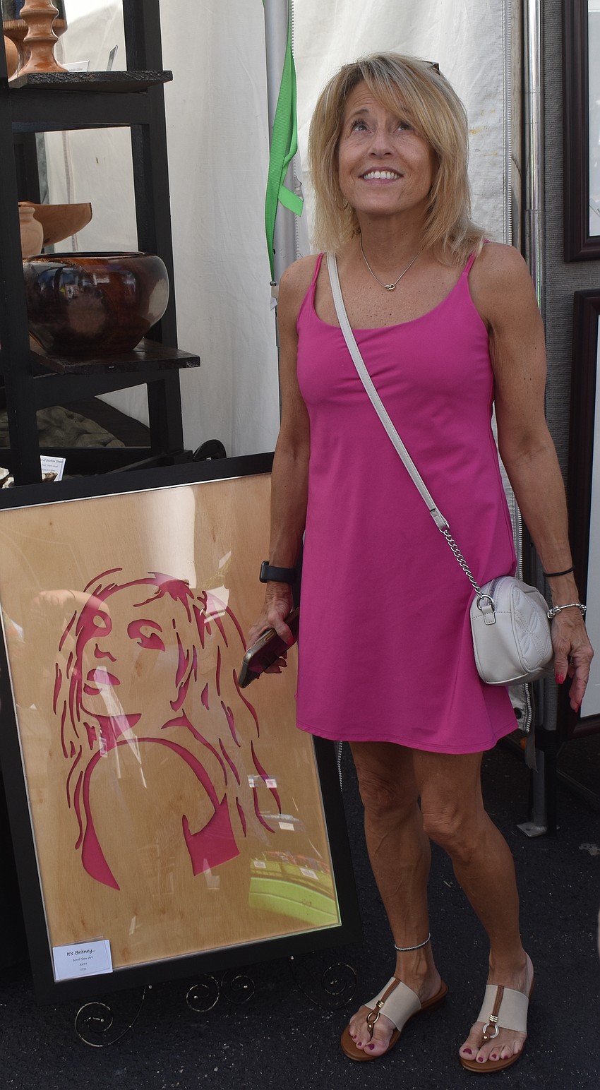 Parrish's Glenda Barfell poses for a photo with a handmade wood art piece by From the Heart Wood Designs because 