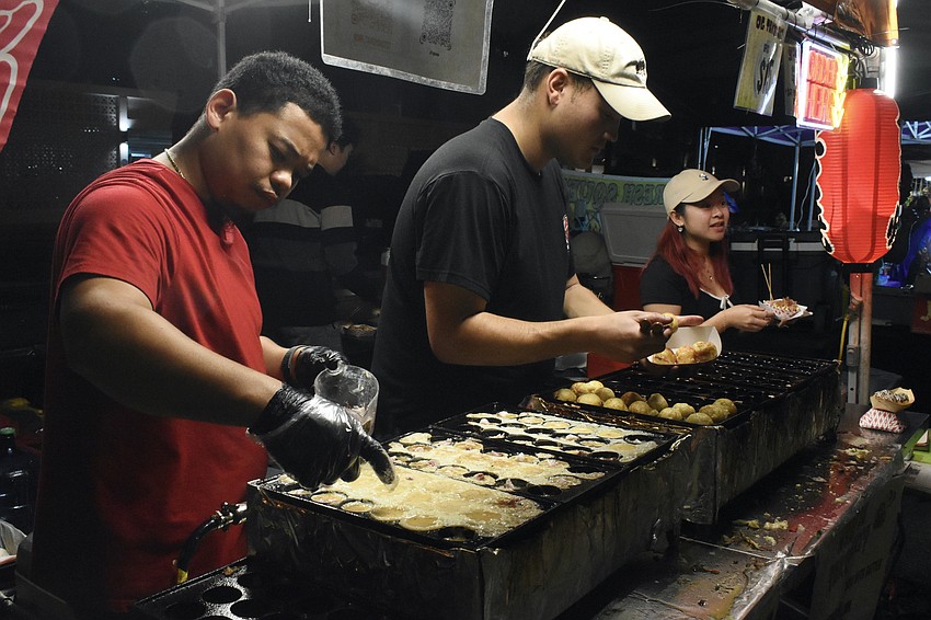 Lam To, Justin Nguyen and Kathy Doan of Mr. Takoyaki prepare orders of takoyaki, a ball-shaped Japanese dish of fried dough stuffed with savory ingredients.