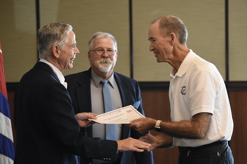 Lt. Ron James stands beside Executive Officer Samuel Doak, as Ron Babinsky is presented with the Excellence in Teaching Award.