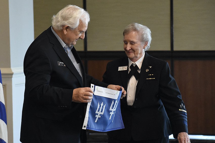 Past Commander Leon Warshaw passes the flag to Past Commander Susan Lomastro.