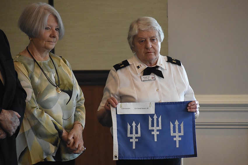 Past Commander Barbara Wolfe stands beside Past Commander Roxanne Fox as she holds the flag.