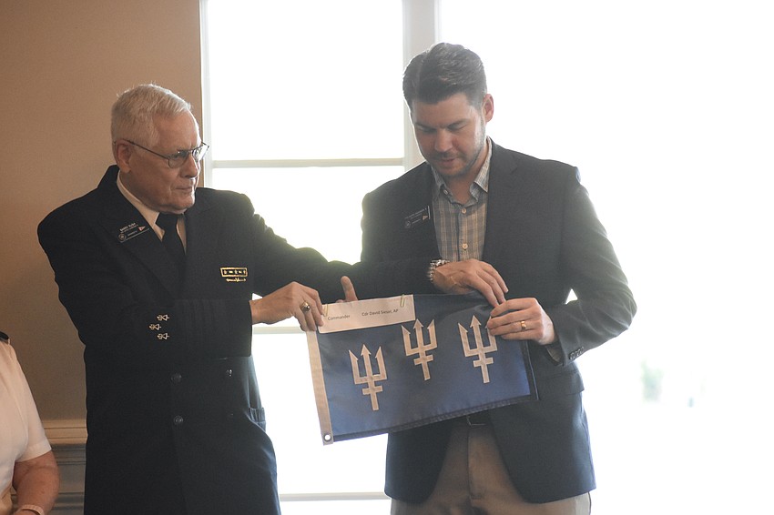 Past District Commander Barry Rush hands the flag to Past Commander Austin Dickinson.
