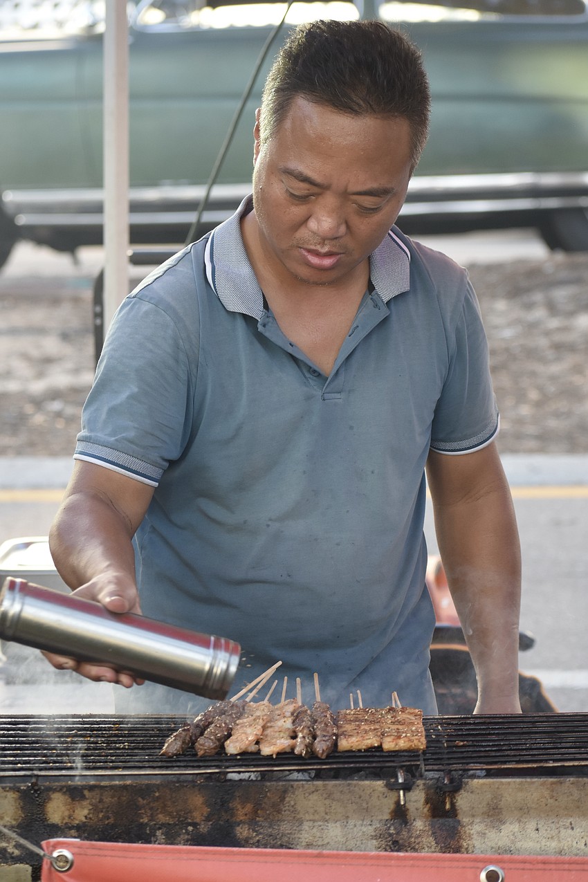 Jinglong Yin of G&S seasons the meat skewers he is grilling.