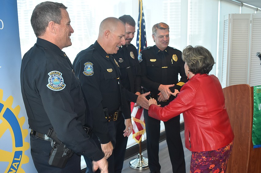 Lieutenant Bruce King, Captain Robert Armstrong, Officer Michael Skinner (representing honoree Ron Dixon) and Lieutenant Jamie Adams of the Sarasota Police Department shake hands with Rotary Club of Sarasota president Pam Akins.