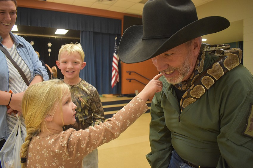 Lorielle and Elias Conner watch as Heartlee Conner pets a ball python held by Rob Hendrickson.