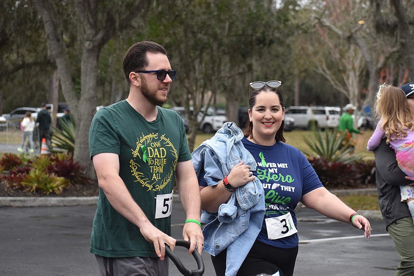 Gage and Alexis Sosso, parents of 2-year-old Aria who attends All God's Children Preschool, walk during the Miles for the Miles Family Cozy Cocoa Dash.