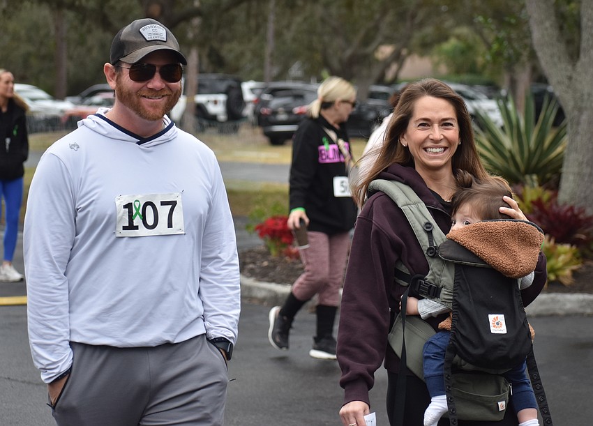 Cary and Sarah Verasco, along with baby Charlie, walk during the Miles for the Miles Family Cozy Cocoa Dash. They have had three kids graduate from All God's Children Preschool.