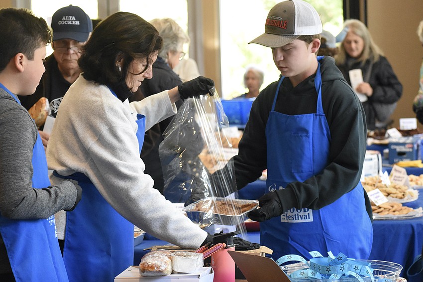 Ethan Freeman, 14, Roberta Gerlach, and Skate Segal, 14, package an item.