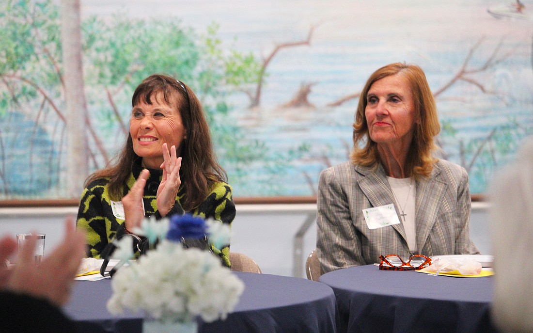 Ann-Marie Thompson and Cheryl Mulherin, attendees at the St. Mary, Star of the Sea, Catholic Church Women's Guild new members luncheon on Jan. 29, applaud the soon-to-be-outgoing board members.