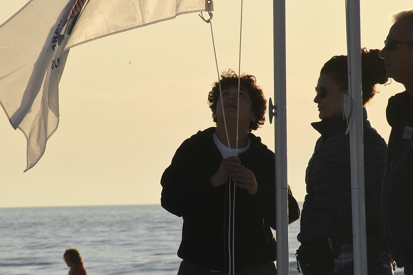 Blayton Bidlestone, 13, raises the Coast Guard flag, standing beside Vanessa Lima, who raised the Space Force flag, and James 