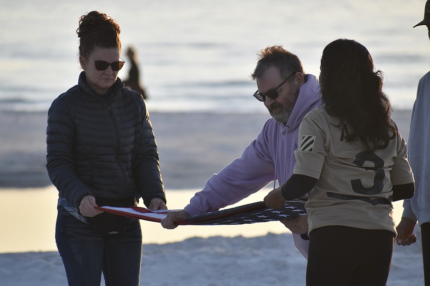 Vanessa Lima, Wayne Bundy and Maria Guardado fold the American flag.