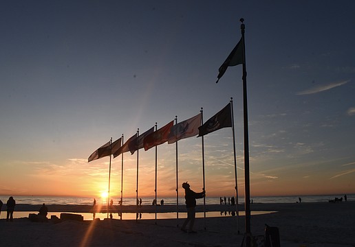 Thomas Modly adjusts the flagpoles as the sun sets.