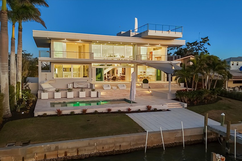Walls of windows and a rooftop deck showcase views of the water.