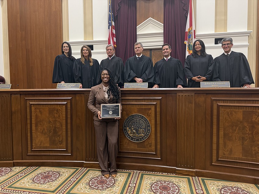 D.W. Perkins Bar Association President Naphtalie Azor accepted the state Supreme Court’s 2026 Voluntary Bar Association Pro Bono Award on Jan. 22 in Tallahassee. Standing, from left: Justice Meredith Sasso, Justice Jamie Grosshans, Justice Jorge Labarga, Chief Justice Carlos Muñiz, Justice John Couriel, Justice Renatha Francis and Justice Adam Tanenbaum.
