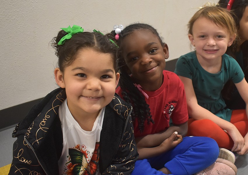 Kindergarten students Aniyah Godgiben, Kaleigh Payton and Kinsley Apple sit in the hallway as older students walk by during the Parade of Nations.
