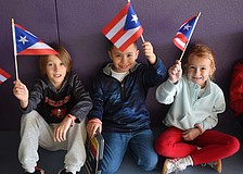 Second graders Jordan Davis, Dominic Michalo and Sloan Middleton wave flags of Puerto Rico, which was the country they were assigned for the Tara Elementary School Olympics.