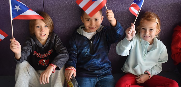 Second graders Jordan Davis, Dominic Michalo and Sloan Middleton wave flags of Puerto Rico, which was the country they were assigned for the Tara Elementary School Olympics.