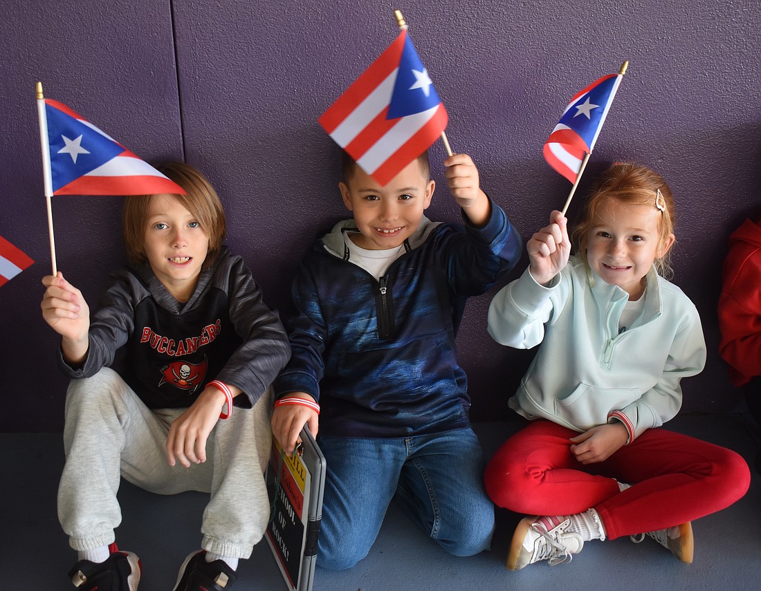 Second graders Jordan Davis, Dominic Michalo and Sloan Middleton wave flags of Puerto Rico, which was the country they were assigned for the Tara Elementary School Olympics.