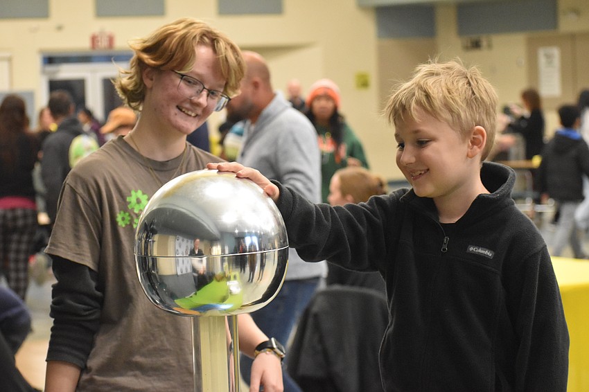 Eleventh grader Lee Lopin helps second grader Jack Souter experience static electricity.