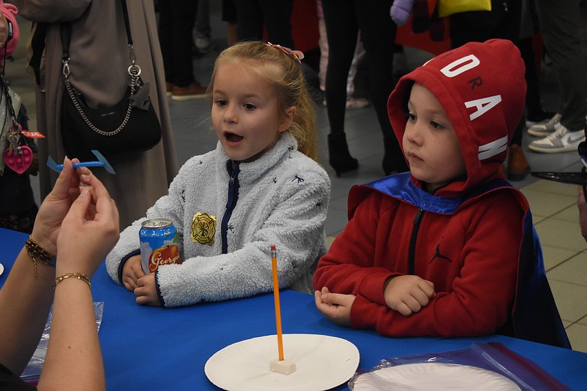 Kindergarteners Kaya Kozlowski and Kaleb Roberts look watch a craft demonstration.