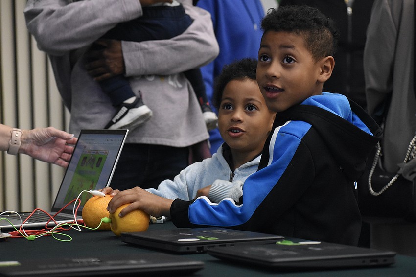 Pre-K student Elijah Adamo and first grader Giovanni Adamo control a video game with oranges.