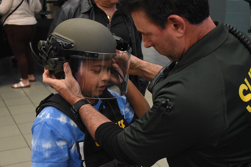 Fifth grader Gabriel Socorro receives a helmet from Deputy Michael De Leo of the Sarasota County Sheriff's Office.