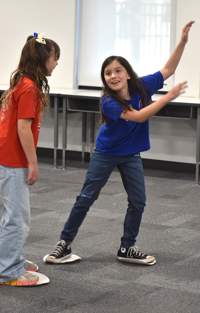 Reagan Lehnert and Phoebe Aulman, second graders at Tara Elementary, use paper plates as ice skates in the figure skating activity.