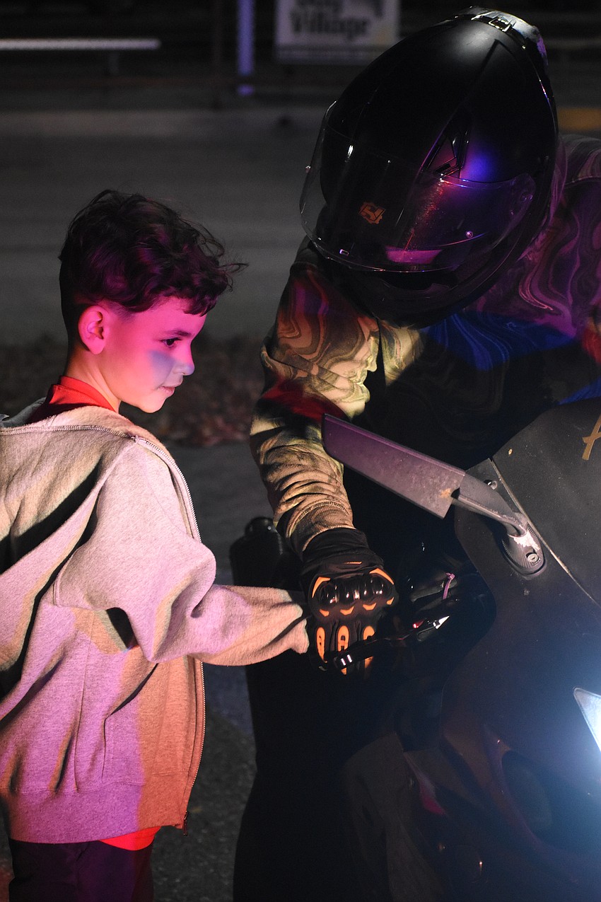 Third grader Daniel Cortez revs the engine on Angel Ramahi's motorcycle as she takes off.