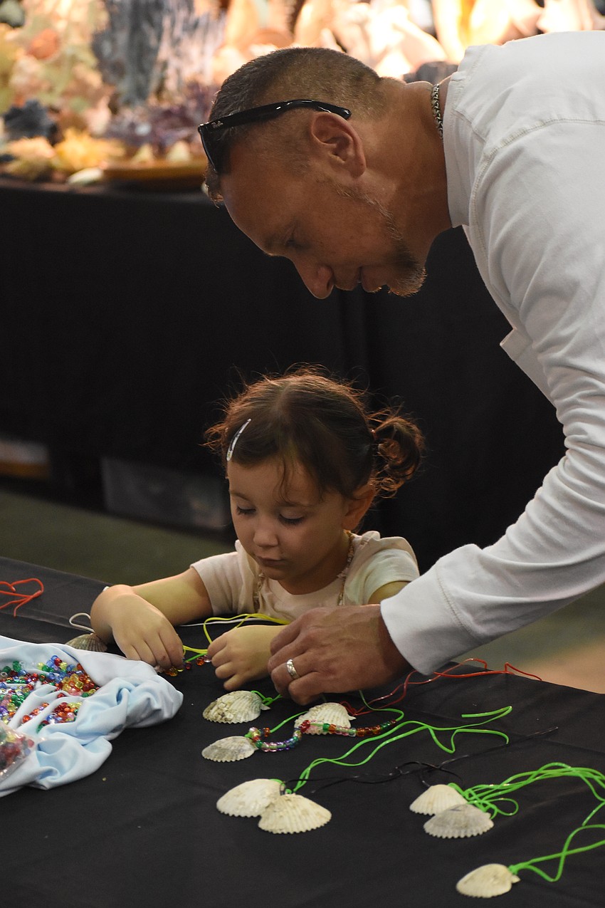 Olivia Gartner, 3, and Aaron Gartner work on a the craft project of a beaded shell necklace.
