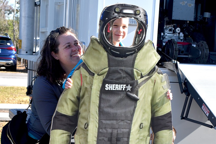 Greenbrook's Stephanie Tretolo gives her 5-year-old son Oliver a boost to take a photo in the sheriff's cutout.