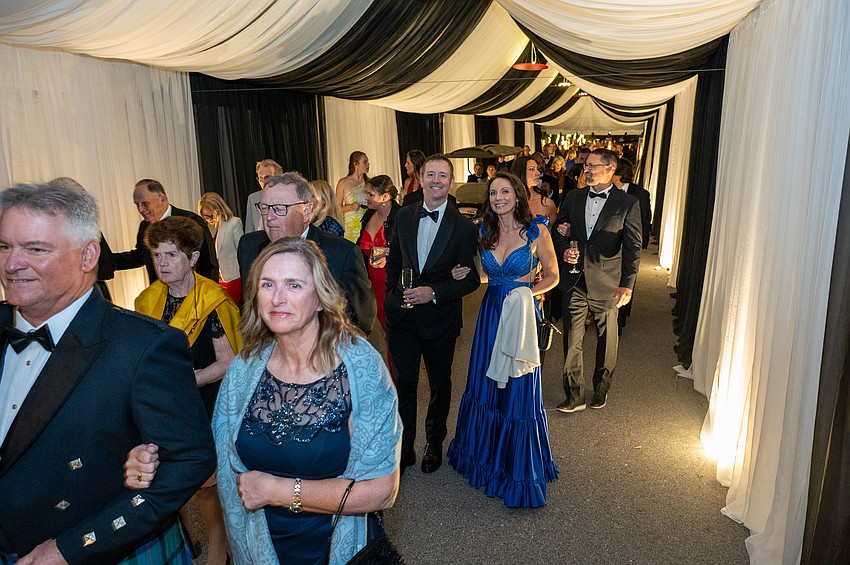 Guests move through a long curtained walkway to the tent where dinner will be served.