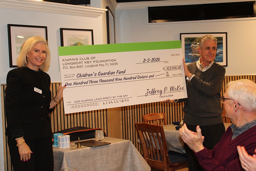 Kiwanis Club of Longboat Key members applaud the unveiling of a check to the Children's Guardian Fund supplied through Lawn Party fundraising efforts. The club ended up making a total $123,900 contribution with matching funds from supporters.