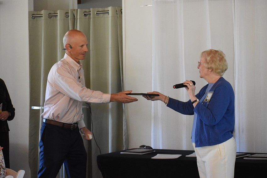 Tom Edwards accepts a plaque from Sharon Davisson.