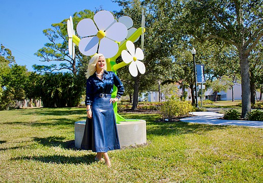 Artist Michelle-Marie Heinemann recently created the non-profit Flower Tree Foundation to facilitate bringing art installations to public spaces. She stands next to a larger-than-life statue that is part of her daisy series of statues, the first public installation she brought to the New College of Florida.