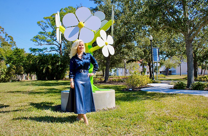Artist Michelle-Marie Heinemann recently created the non-profit Flower Tree Foundation to facilitate bringing art installations to public spaces. She stands next to a larger-than-life statue that is part of her daisy series of statues, the first public installation she brought to the New College of Florida.