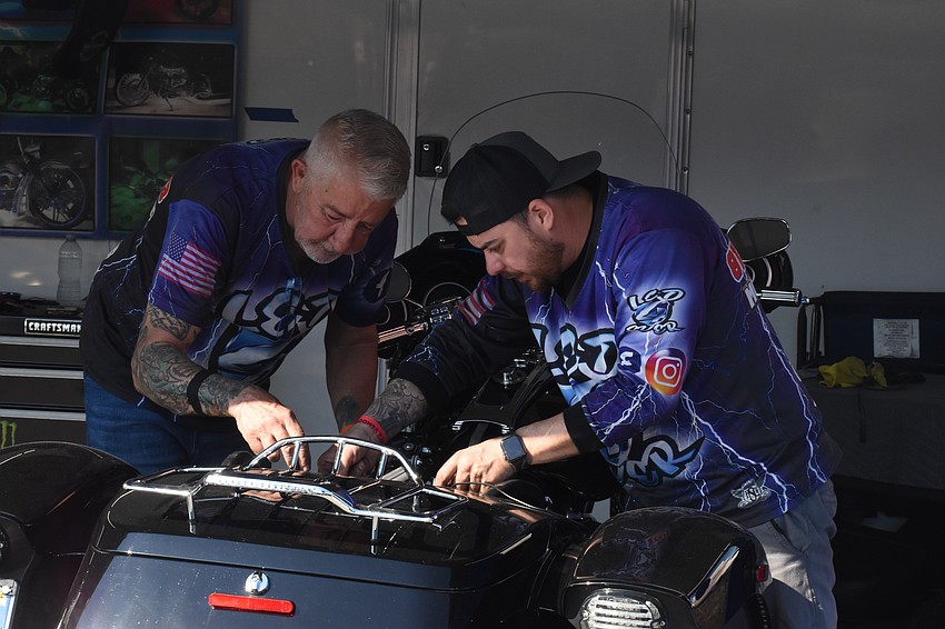 Earl Baldwin and Manny Gonzalez work on a vehicle at the LED4Ever tent.