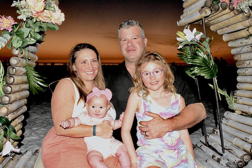 Caitlin MacDonald, 6-month-old Ava MacDonald, Kevin MacDonald and 9-year-old Ella MacDonald pose in a photo area.