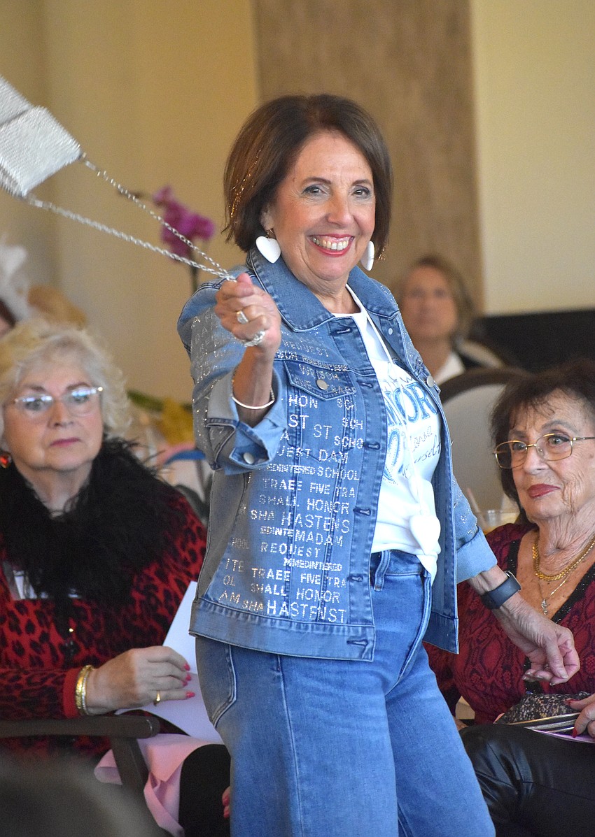 Pat Reinhart adds a touch of fun to her denim outfit by swinging the silver purse around as she models the look by Darci's boutique.