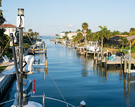 Boat lifts flank each side of the canal in a Country Club Shores neighborhood. The town of Longboat Key is preparing to enact a continuous canal maintenance program that would include flat fees and ad-valorem assessments for residents.